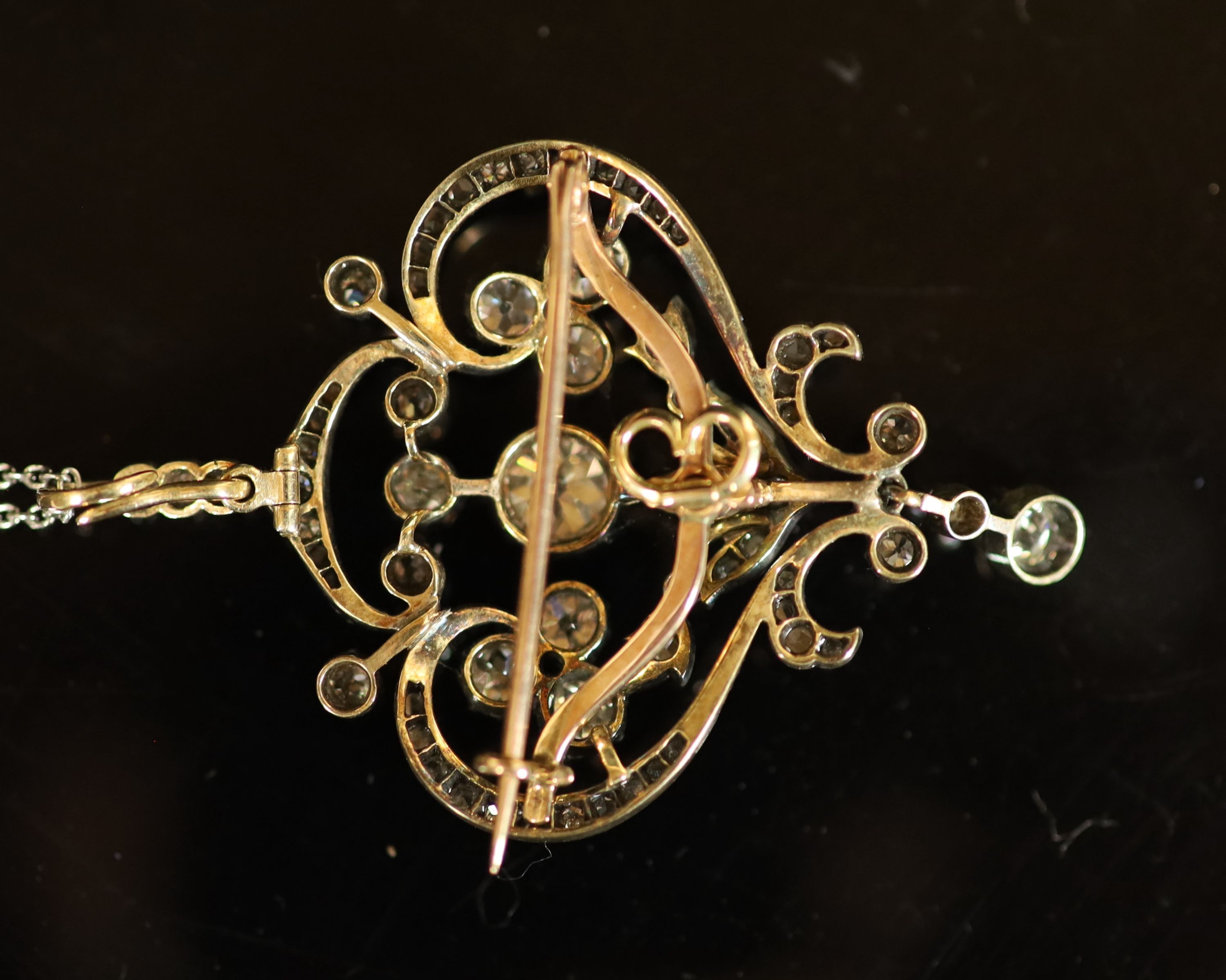 A 19th century gold, silver and diamond set open work scroll drop pendant brooch, together with a white metal chain